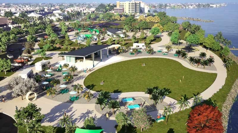 Aerial view of a large park in Southwest Florida with open green space, walkways, scattered palm trees, small buildings, and a waterfront in the background—an ideal landscape for thoughtful construction management.