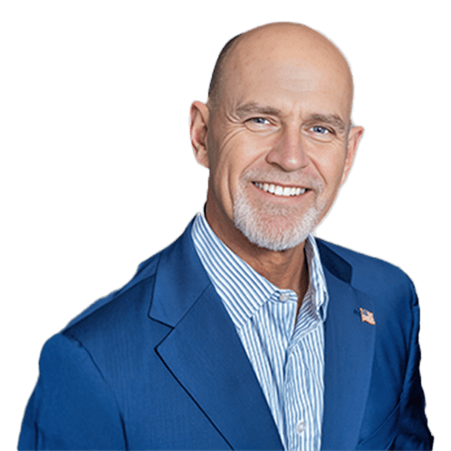 A middle-aged man with a bald head and gray goatee, wearing a blue suit jacket over a striped shirt, smiles at the camera against a plain background—an experienced Construction Management professional from Southwest Florida.